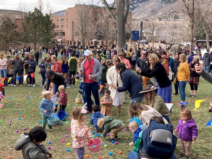 A crowd of people in Parfet Park with children stooping to pick up Easter eggs.