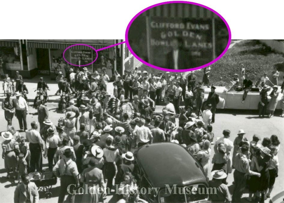 black and white image shows a crowd watching a parade. Clifford Evans Golden Bowling Lanes in background