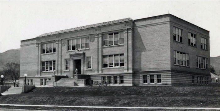 black and white image of 2 story brick school building, 1920s style, mountains in background