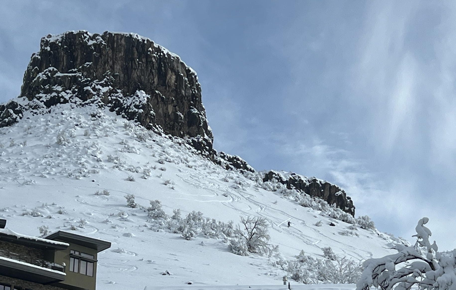 looking up at Castle Rock. The mountainside is snowy and a skier heads downhill, surrounded by several ski trails