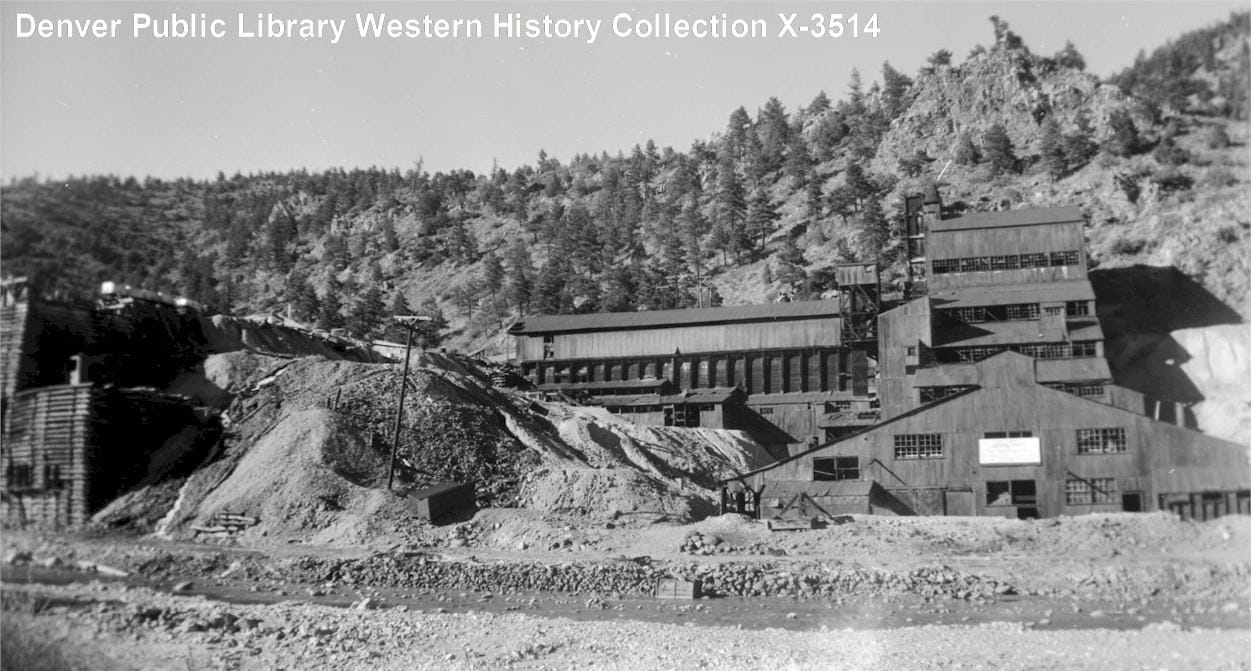 big industrial building on the side of a mountain will crushed rock (mill tailings) next to a creek