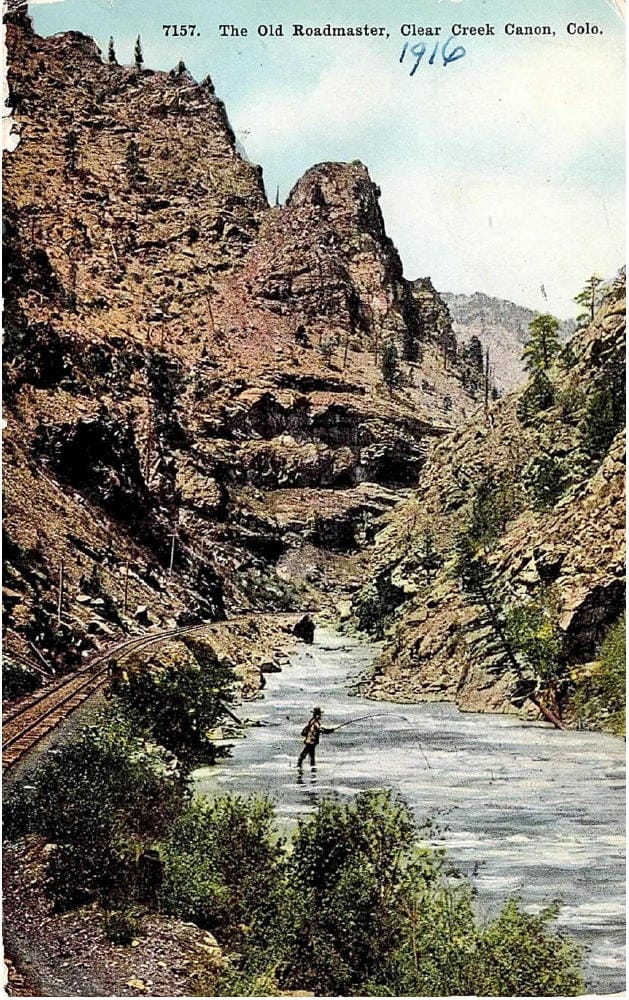 Hand tinted postcard shows fly fisherman in the creek below the railroad tracks in Clear Creek Canyon