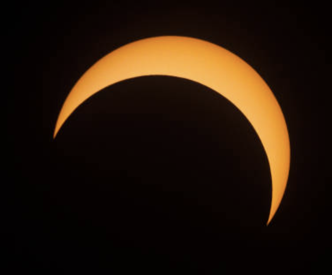 photo showing a yellow-orange crescent of sun in the upper-right hand quadrant against a black background