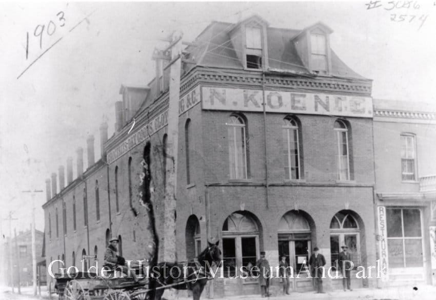 2-story brick commercial building the arched windows and a third-floor dormer. Sign says N. KOENIG