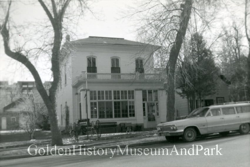 2-story 4 square Victorian house with a sun porch in front and a balcony over the porch. 1968 Chevy wagon in front