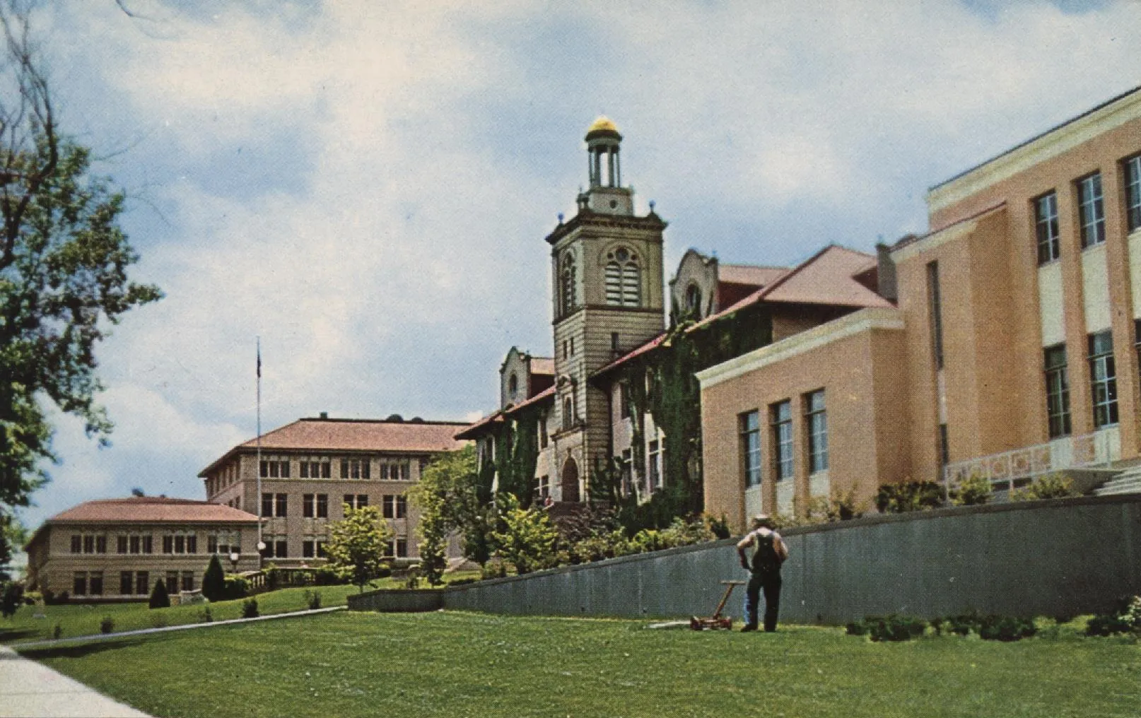 Postcard showing Berthoud, Guggenheim, and Arthur Lakes buildings, circa 1970.  Man pushing lawnmover.