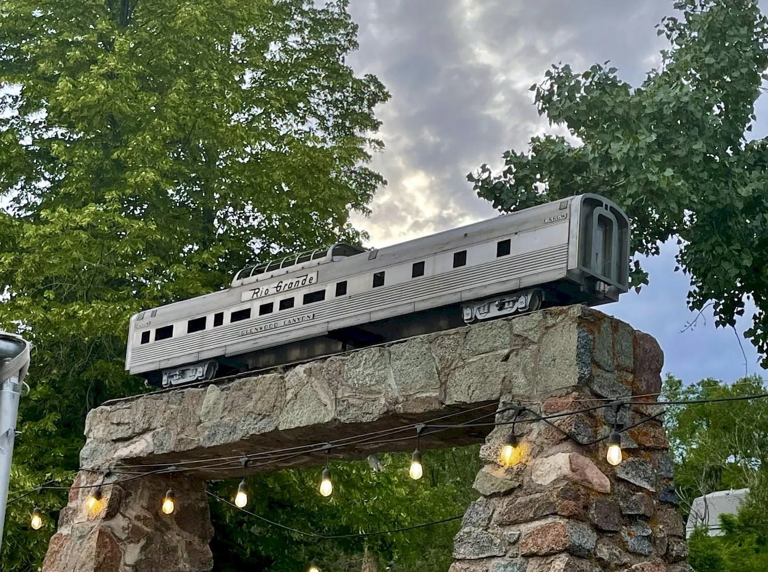Reproduction of a silver passenger car with dome roof section atop a stone trilithon 