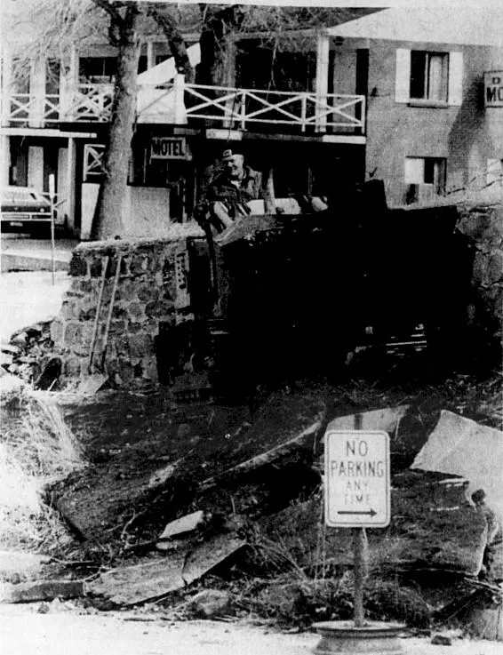 Man operating a small bulldozer, carefully maneuvering around a No Parking Any Time sign