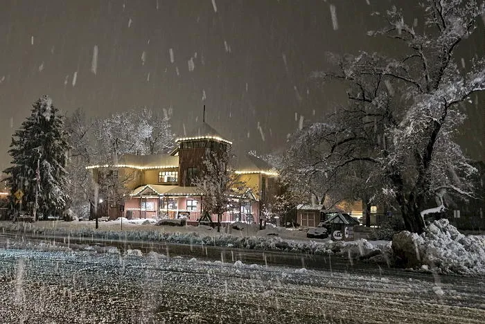 Nighttime photo of the Golden Visitors Center with snow falling and snow on the ground.
