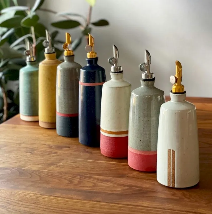 7 ceramic oil pourers of varying shapes, sizes, colors, and patterns