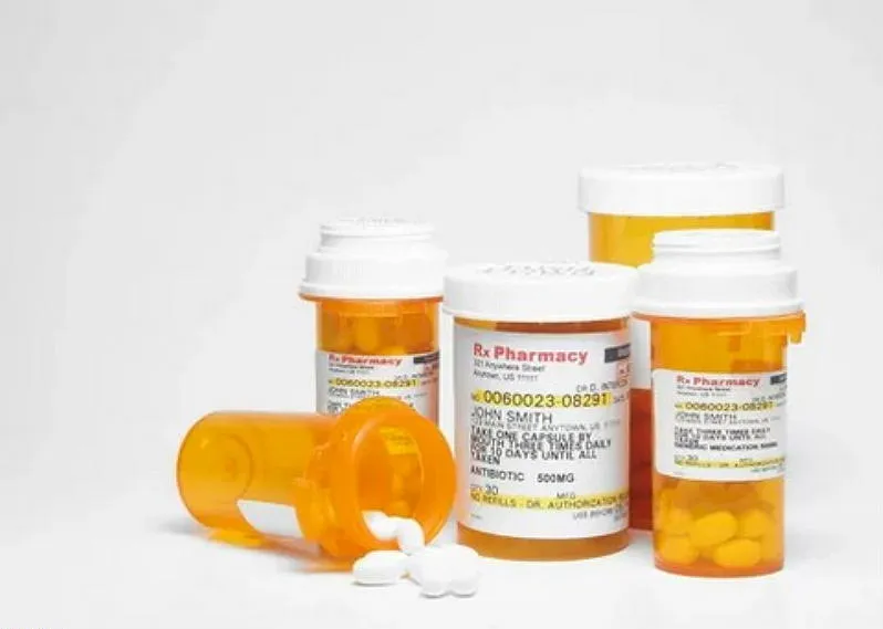 5 prescription bill bottles, one with white pills poured out