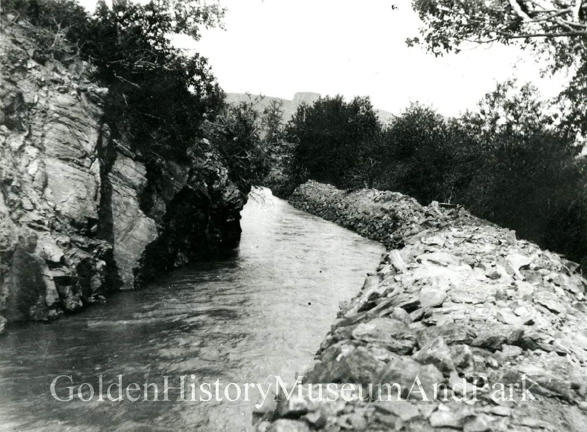 fast-running ditch with loose rock bank on one side and high native rock bank on the other - Castle Rock in background