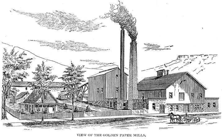 Two 2-story industrial buildings with two smokestacks,a small cottage in a fenced yard next door, and team and wagon in front