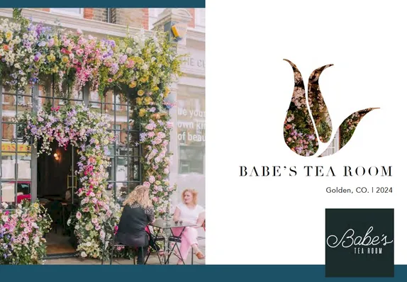 Two women sharing a table in front of a flower-covered business.