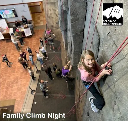 Young girl rappelling on the climbing wall at the Mountaineering Center.  Other people far below.