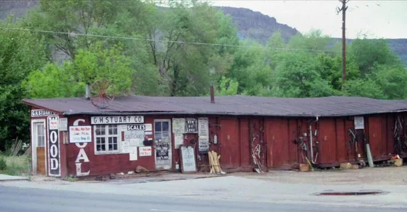 A long red wooden shed with signs saying WOOD, COAL, G.H. Stuart Co., and Scales