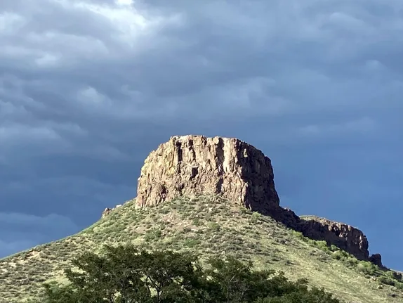 shows the South Table Mountain rock formation called Castle Rock.  Storm clouds in the background.