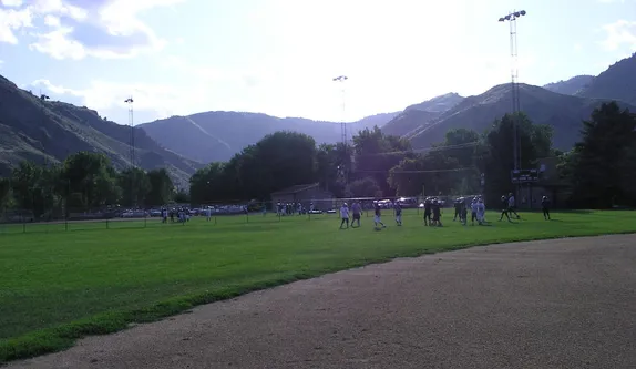 football players on a green field in the distance with mountains in the background