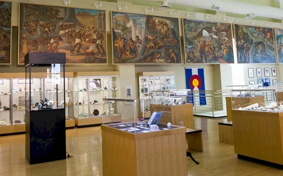 Interior of Mines Museum - display cases of rocks & minerals and large paintings of the history of mining