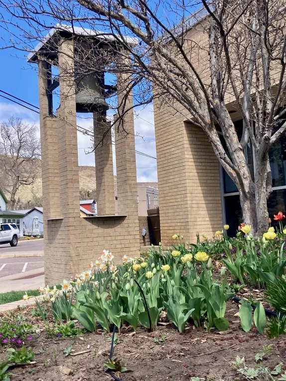 spring flowers at the base of the small bell tower in front of Golden's city hall