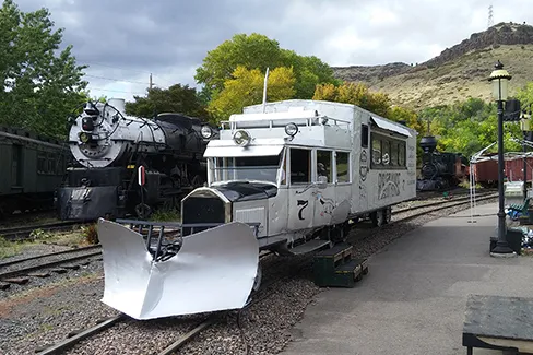 silver-colored hybrid truck-railcar on the track at the Colorado Railroad Museum.  Plow attached to front.