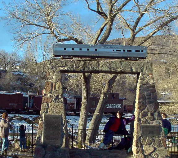 child standing in the monument to the California Zephyr, trains, trees, and patches of snow in the background