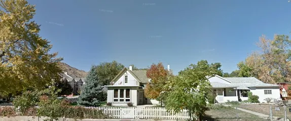 shows 2 small frame homes, one with picket fence surrounding the yard
