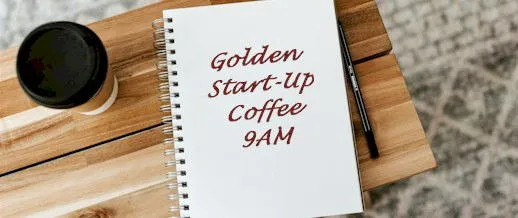 Cup of coffee and a notebook saying Golden Start-Up Coffee 9AM