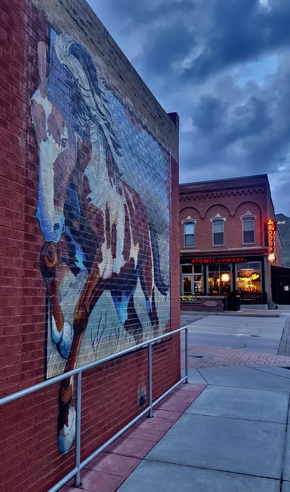 mural of a paint horse on a brick wall - leaden skies overhead - Atomic Cowboy sign illuminated across the street