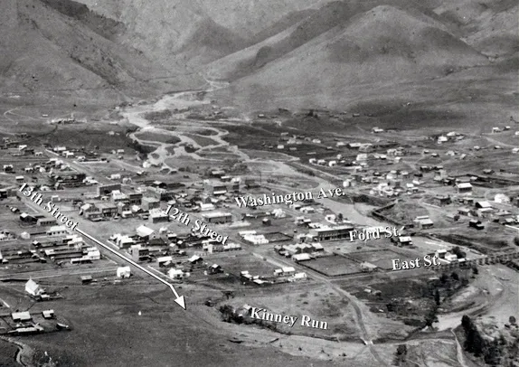 early photo of Golden showing dirt street, frame houses, and a  very wide channel for Clear Creek