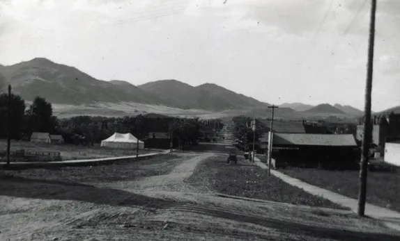 early photo of Washington Avenue, unpaved, with one automobile in sight - large tent on the left,approximately 13th St