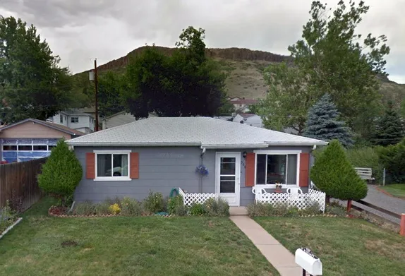 1 story blue-gray house with red shutters - North Table Mountain in backgroun